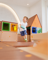 Preschool child developing gross motor vestibular balance on Egoo Cosmotor prone scooter board with teacher support