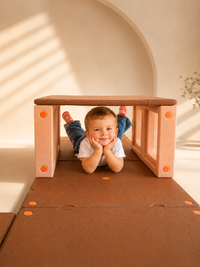 Toddler boy developing gross motor balance and coordination by climbing over gentle incline soft foam wedges on Egoo TiniTerra floor mats.