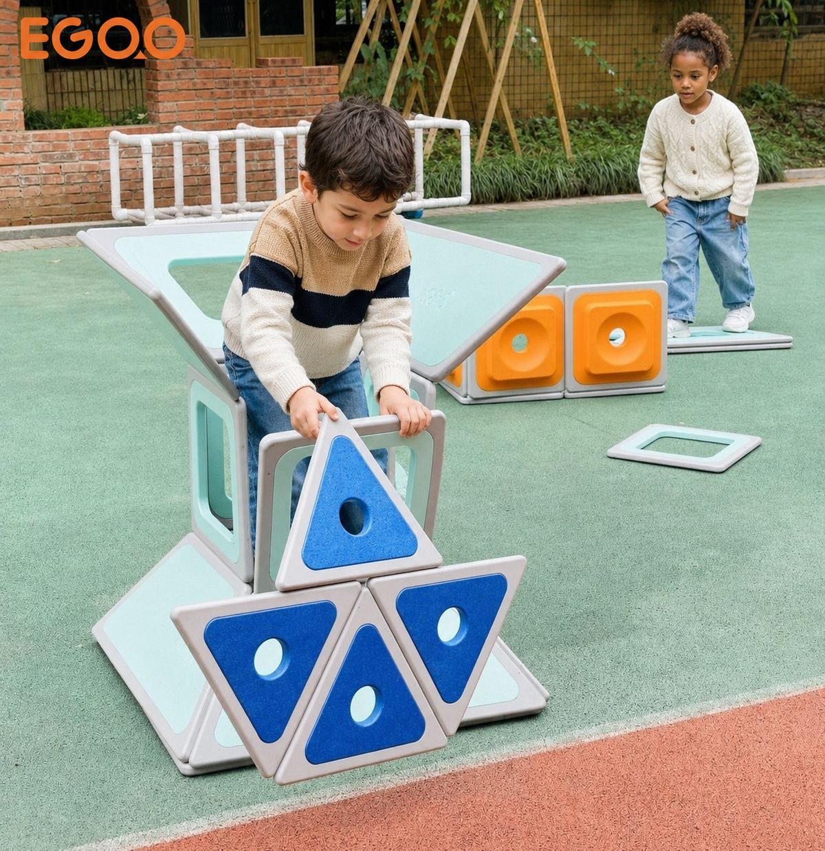 A smiling boy waving from inside an outdoor modular playhouse built with Egoo Magniworld magnetic wall blocks.